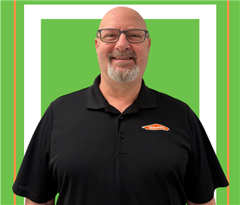 A SERVPRO employee is shown in a black SERVPRO logo shirt