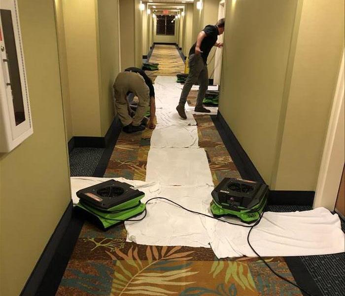 A flooded hotel hallway is shown with restoration equipment