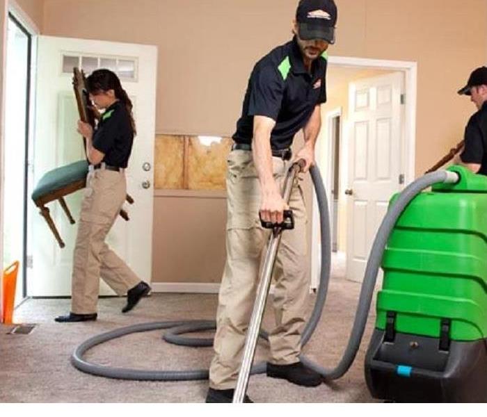 Three SERVPRO techncians are shown cleaning a carpet with SERVPRO equipment