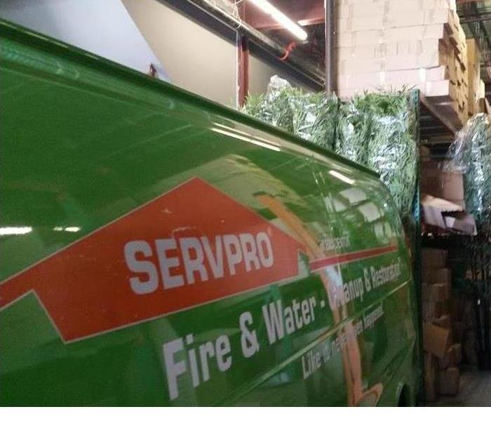 The side of a green SERVPRO truck is shown in a garage